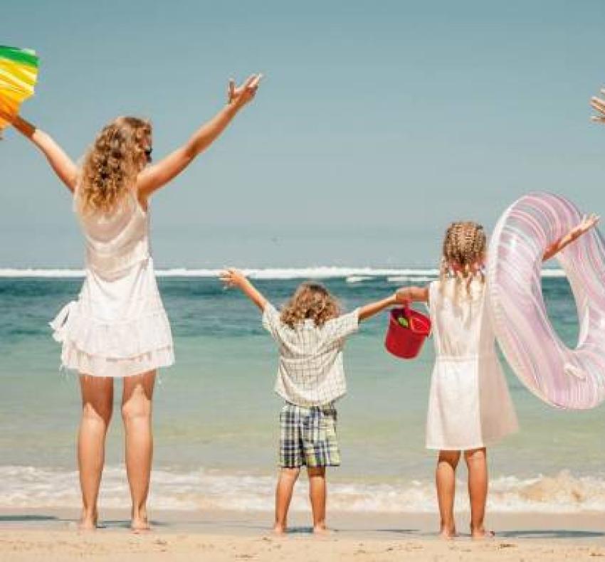 Famiglia felice sulla spiaggia, sole e mare, braccia aperte alla libertà.