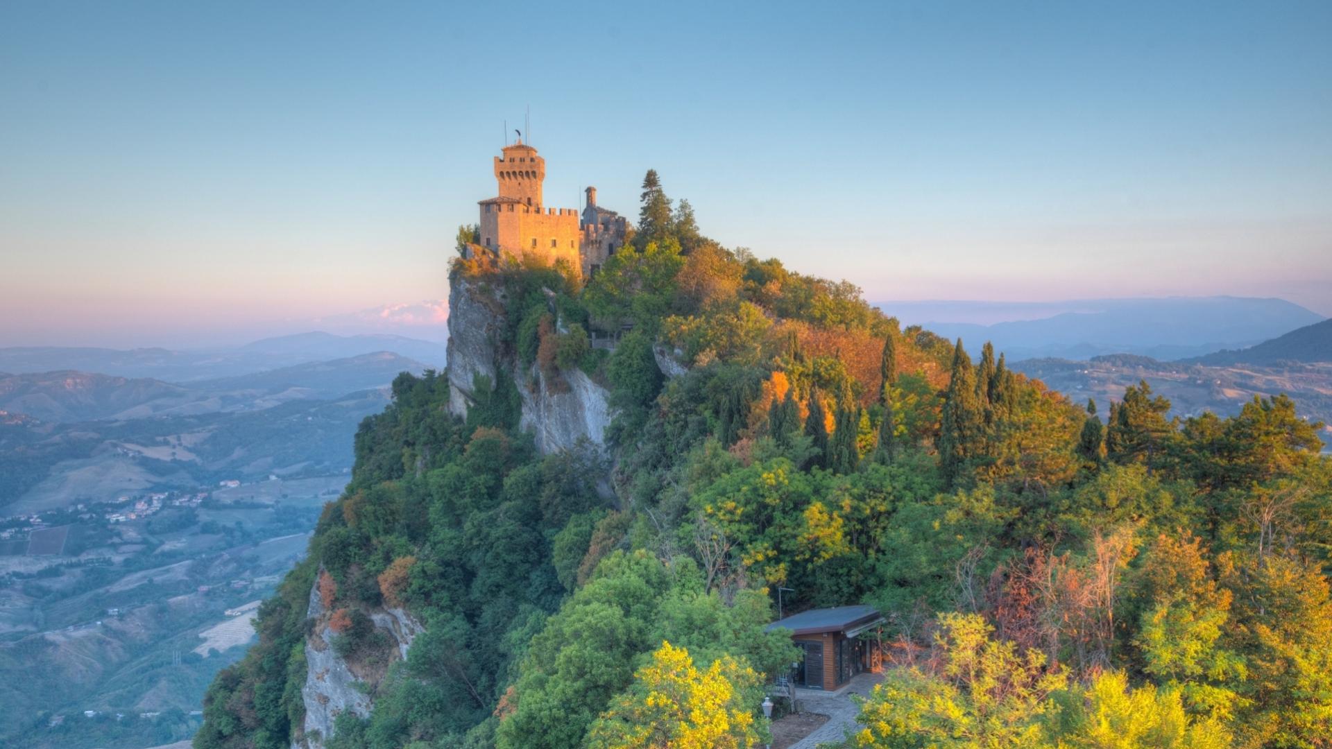 Castello su una collina verde al tramonto, panorama mozzafiato e atmosfera serena.